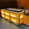 Illuminated golden stone cremation chamber in a modern funeral facility with warm wooden wall panels.