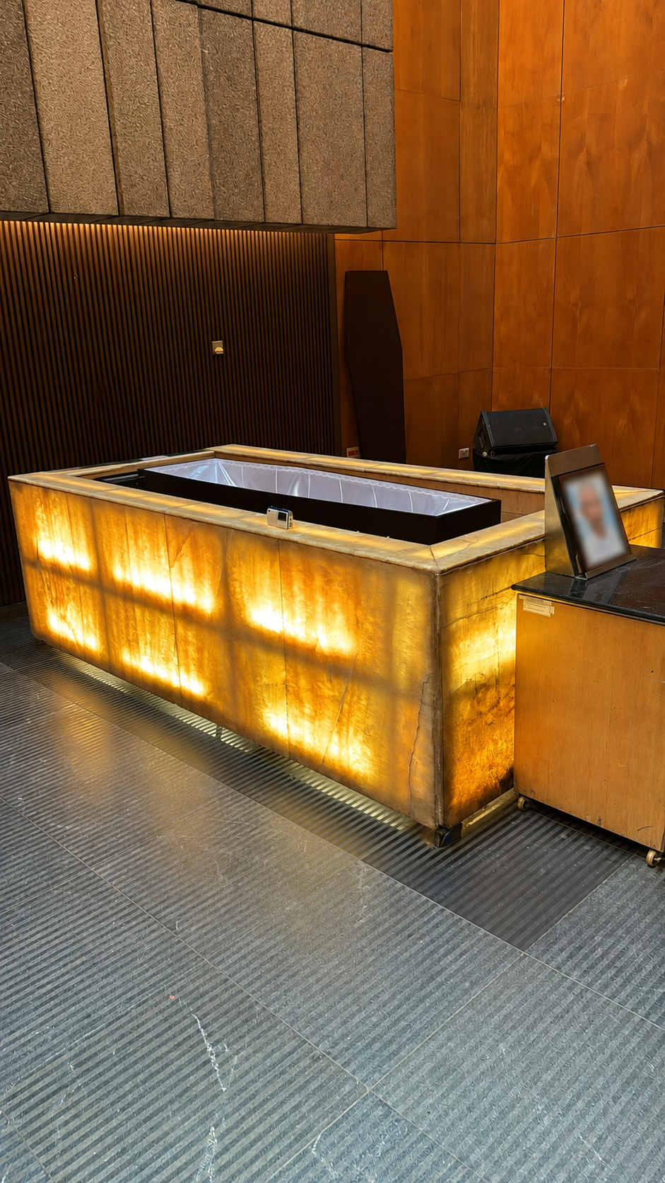Illuminated golden stone cremation chamber in a modern funeral facility with warm wooden wall panels.