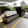 White coffin on a loading platform beside a funeral hearse at a peaceful outdoor funeral facility.